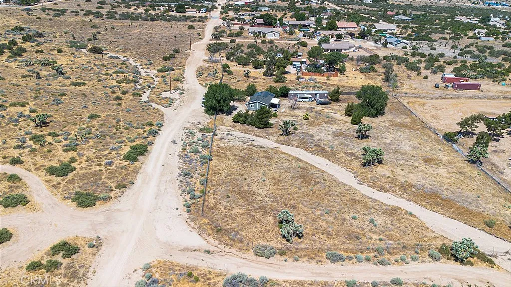 Aerial view of rural land with winding dirt roads, scattered homes, and vegetation.
