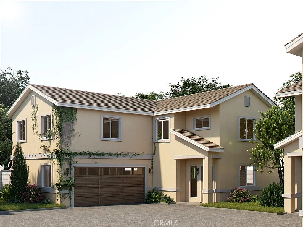 Two-story house with yellow walls, brown garage door, trees, and bushes, California real estate.