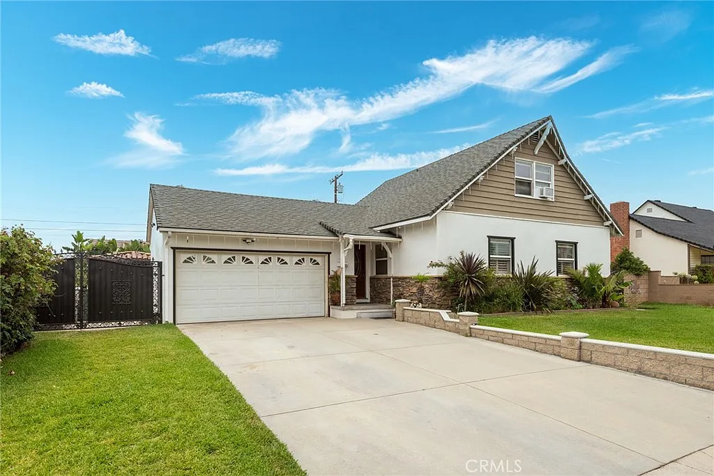 Single-story California real estate house with gray roof, stone accent wall, two-car garage, and front yard grass