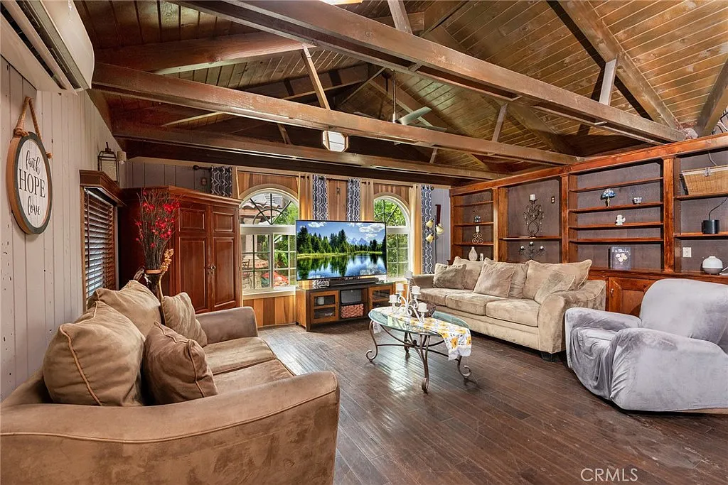 Living room with wooden beams, large TV, coffee table, and comfortable seating