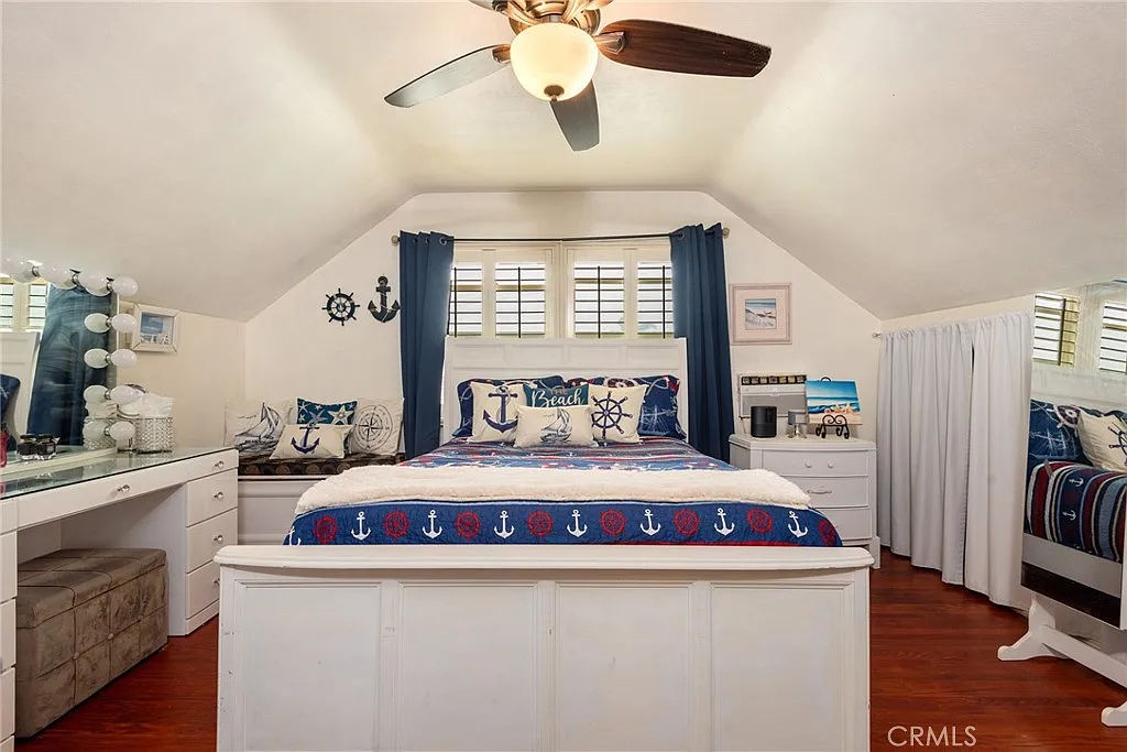 nautical-themed bedroom with bed, anchor-patterned bedding, white furniture, ceiling fan, and wall decorations