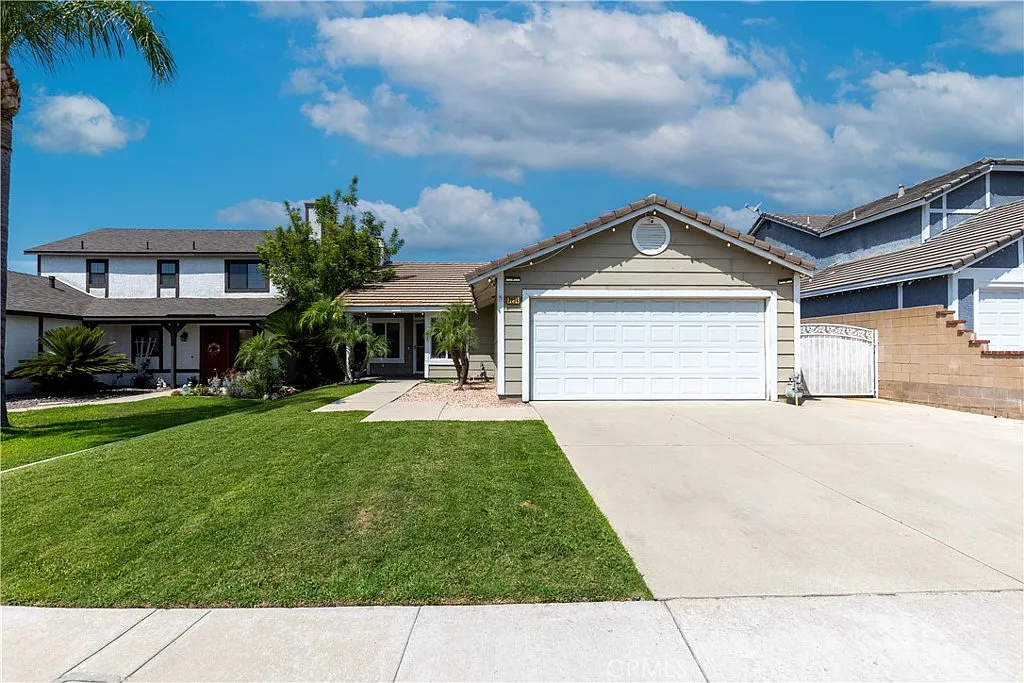House real estate with lawn, driveway, garage, stone siding, and palm trees.