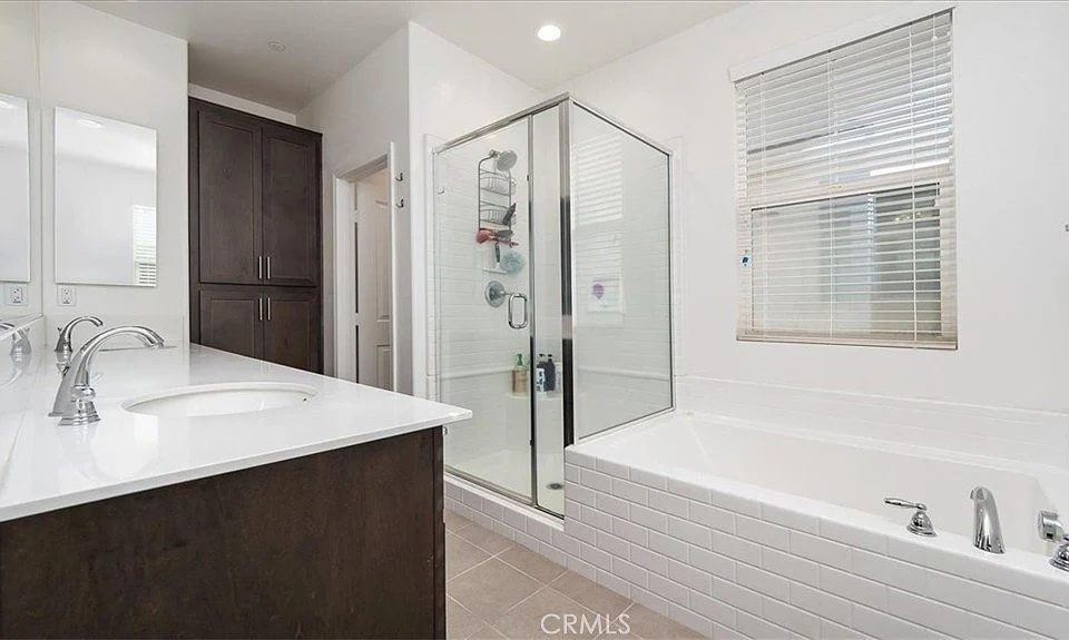 Bathroom with dual sinks, glass shower, and separate bathtub