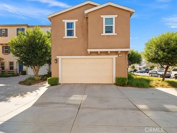 Two-story brown house California real estate with garage, trees, and driveway.