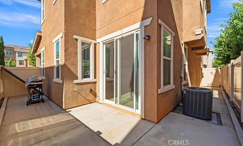 Side of house with patio, sliding glass doors, air conditioning unit, and barbecue grill