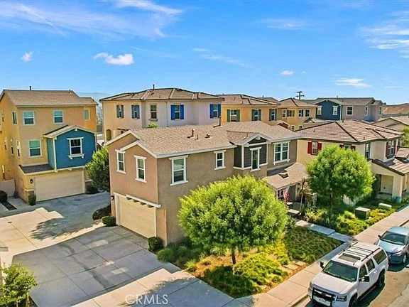Aerial view of residential neighborhood with two-story homes, green lawns, and parked cars