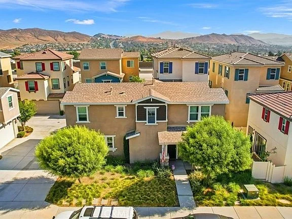Aerial view of residential neighborhood with houses, brown home with landscaped yard, and mountains in background