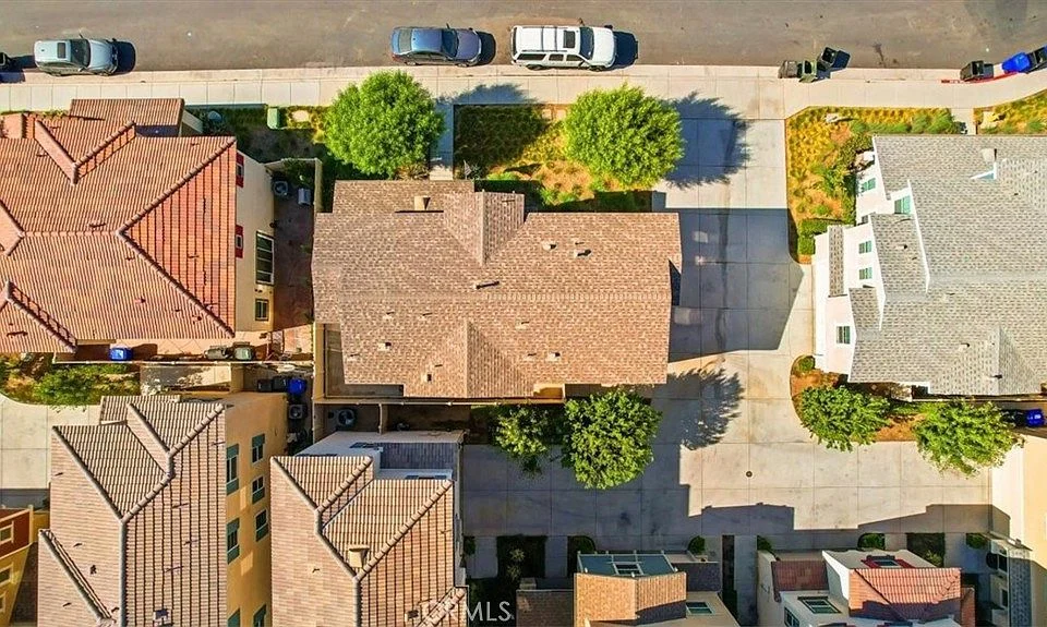 Aerial view of residential neighborhood with houses, tiled roofs, trees, and parked cars