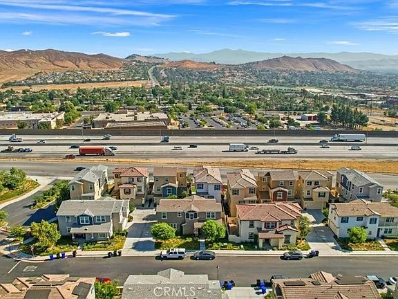 Aerial view of residential area with houses, highway, and surrounding hills
