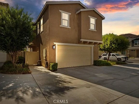 Two-story house real estate with garage, trees, shrubs, and quiet street.