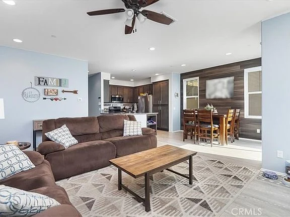 Living room with brown sofa, wooden coffee table, and dining area with dark wood wall and kitchen in background