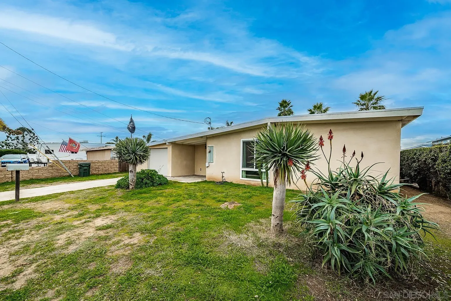 Single-story house real estate with front yard, palm trees, and stone path.