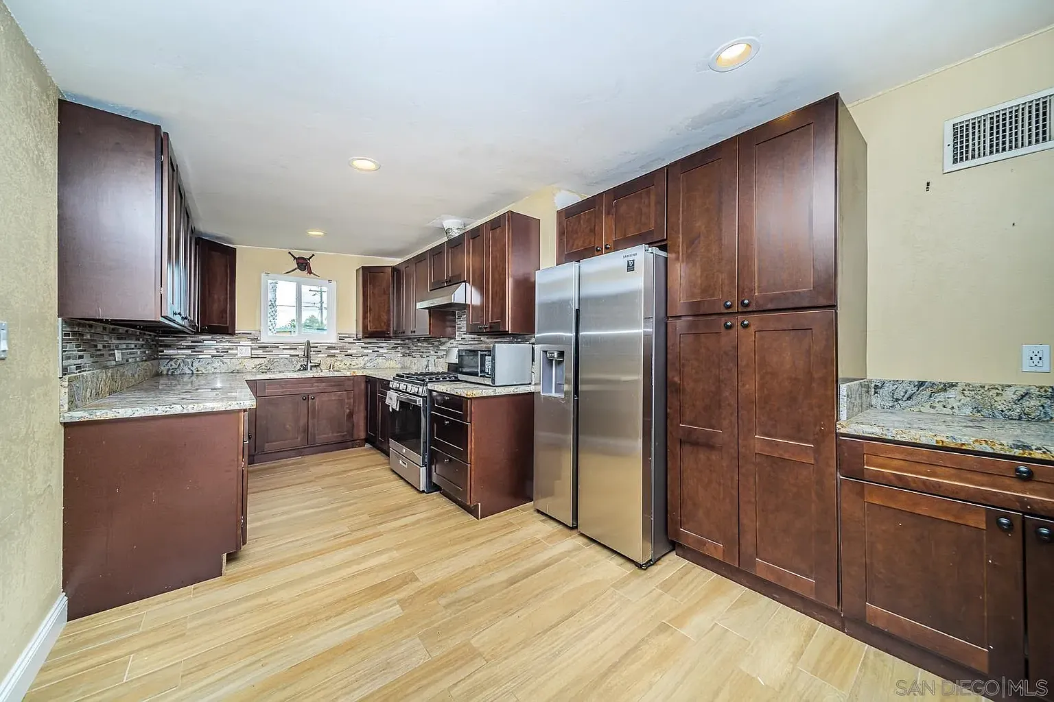 Kitchen with dark wood cabinets, stainless appliances, granite counters, and wood floor.