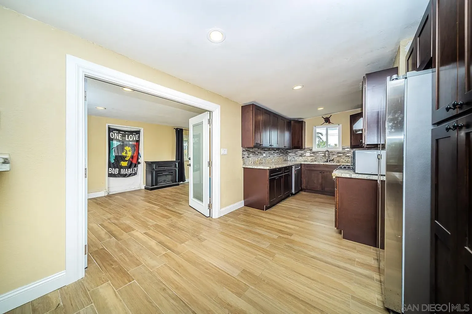 Kitchen with wood cabinets, granite counter, tile floor, and Bob Marley poster.
