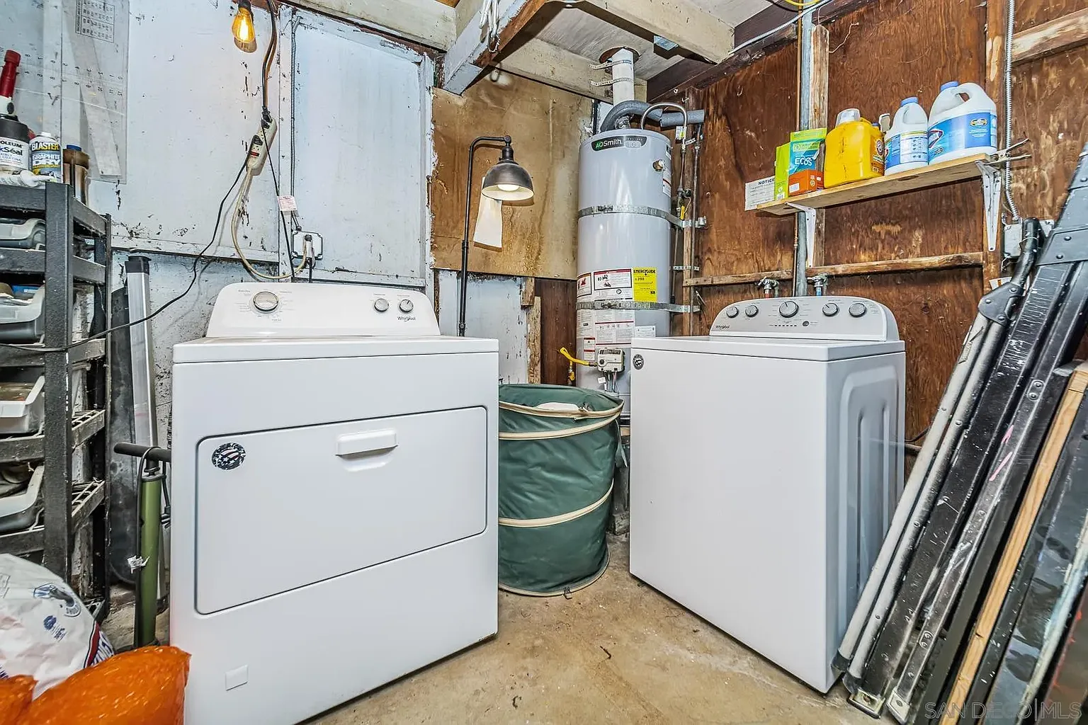 Laundry room with washer, dryer, and shelves with cleaning supplies.