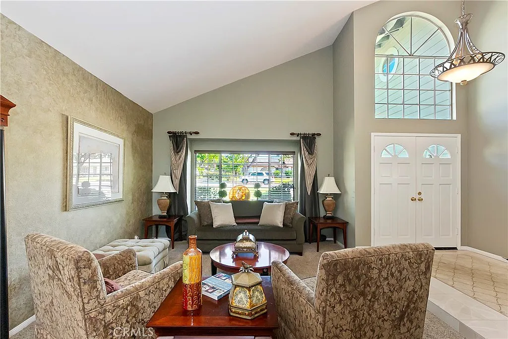 living room with armchairs, wooden table with decorations, lamps, and double doors