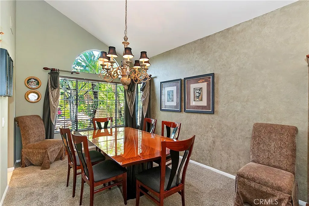 Dining room with large wooden table, chairs, chandelier, and framed pictures on walls