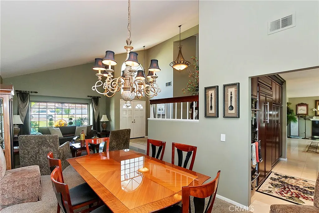 Dining area with wooden table, chairs, chandelier, and open view of living space