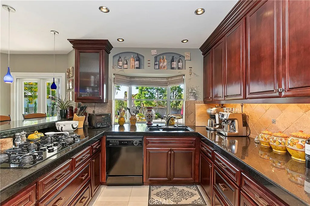 Kitchen with dark wood cabinets, granite countertops, stainless steel appliances, and kitchenware on counters