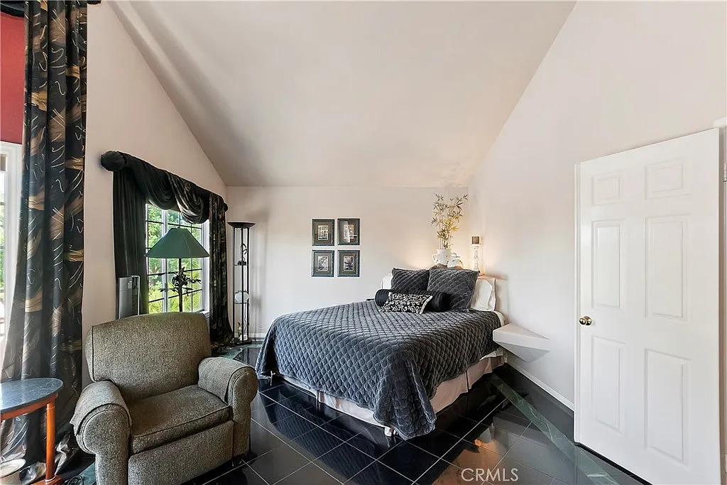 bedroom with queen-sized bed, dark bedding, comfortable chair, modern decor, and large windows