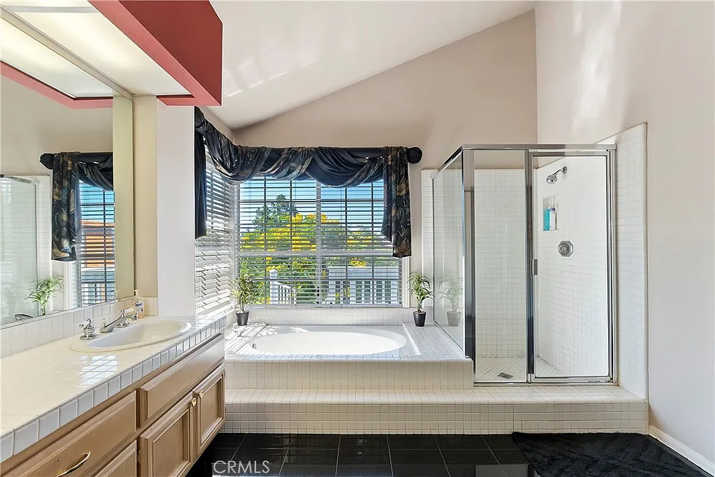 Bathroom with bathtub, glass shower, double sink vanity, and large window.