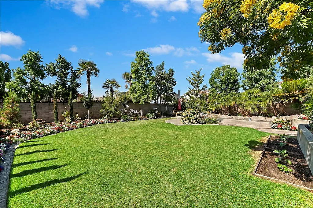 Spacious garden with green grass, flowering plants, trees, stone path