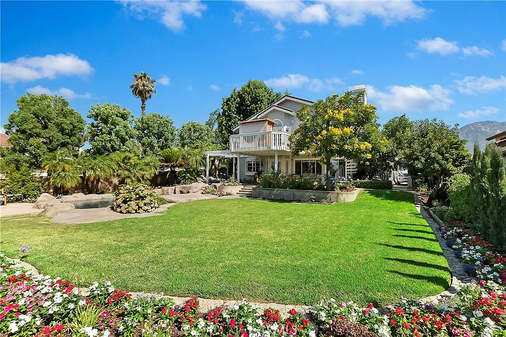 Luxury house real estate with garden, flowers, palm trees, and green plants.