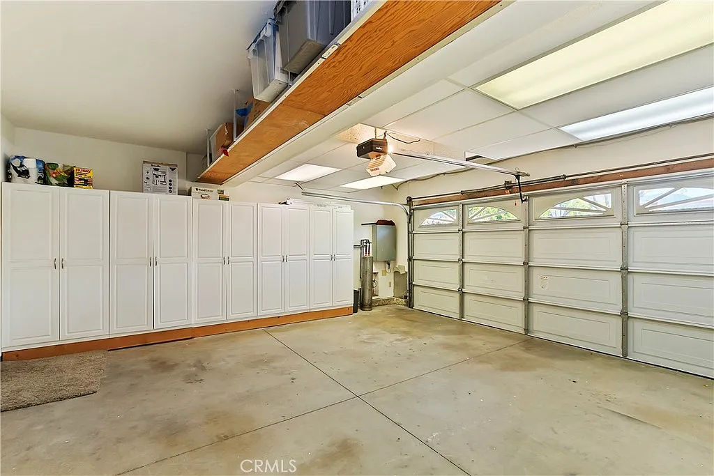 Spacious garage with white cabinets, concrete floor, and large garage door