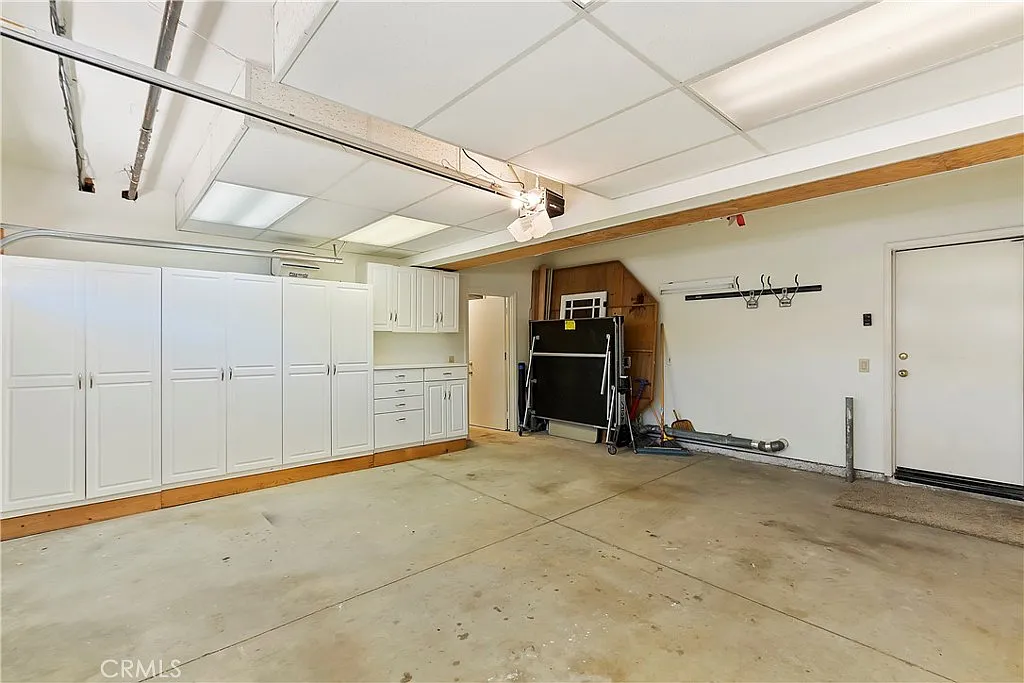 Spacious garage with white cabinets, concrete floor, and open door leading outside