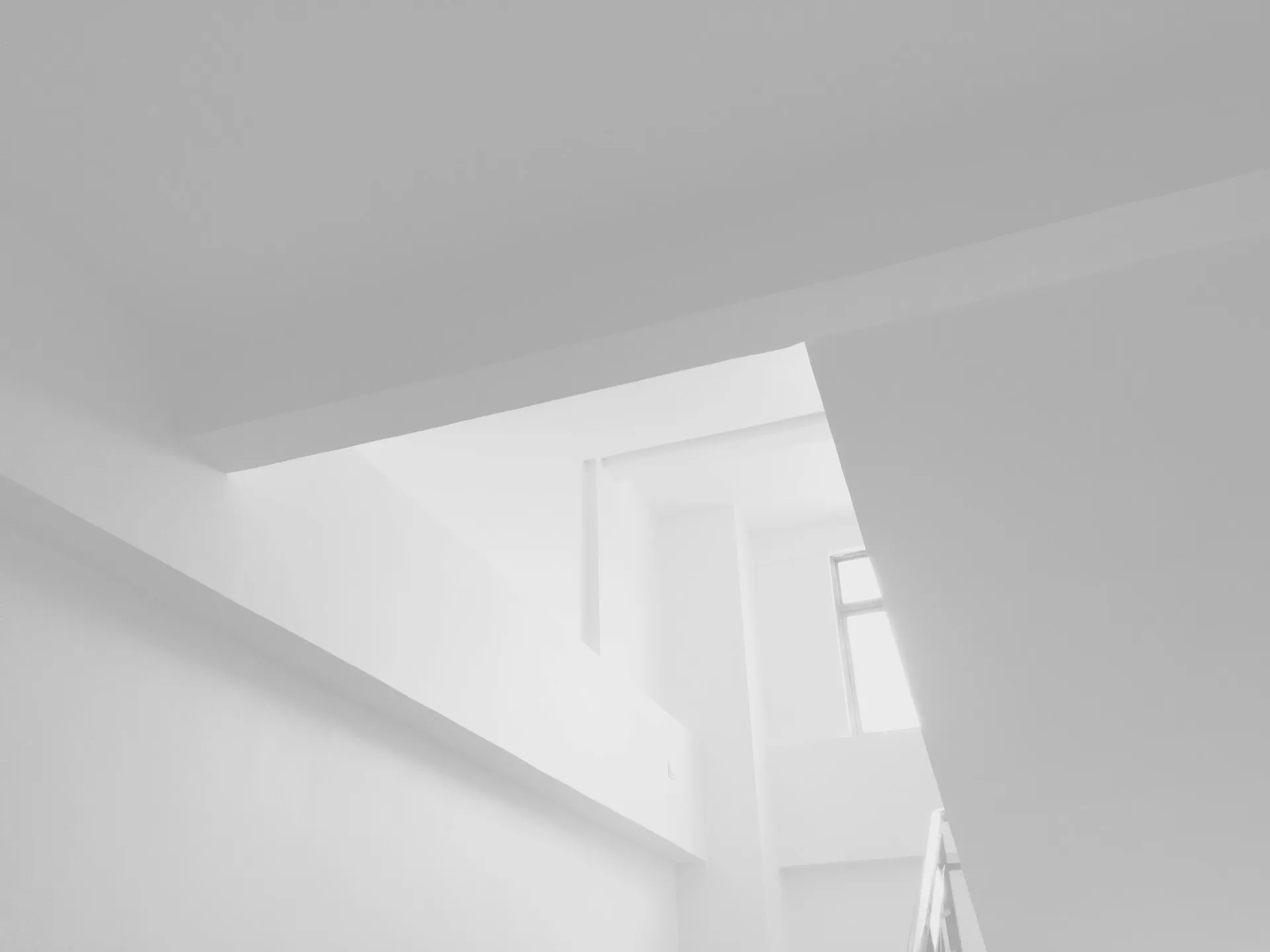 Minimalist interior with white walls, angular lines, and light from window.