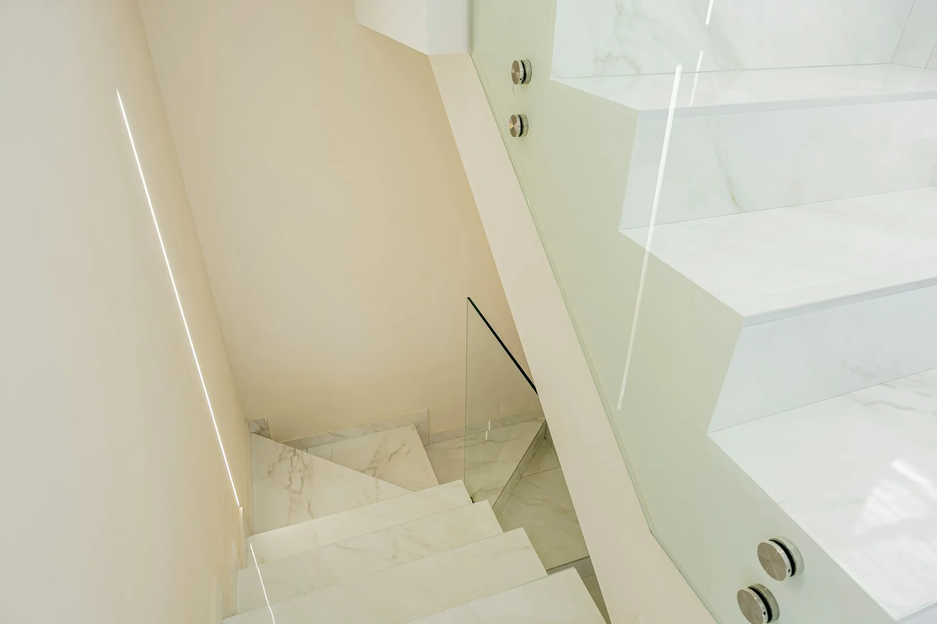 A staircase with glass panels and a simple design leading to a lower level.