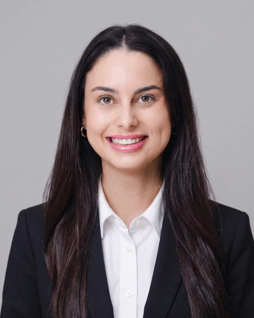Woman with long dark hair smiling at camera, wearing black blazer and white shirt